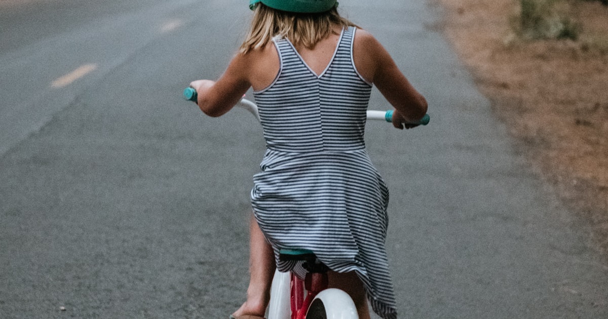 A young girl riding a bicycle on a tree lined road