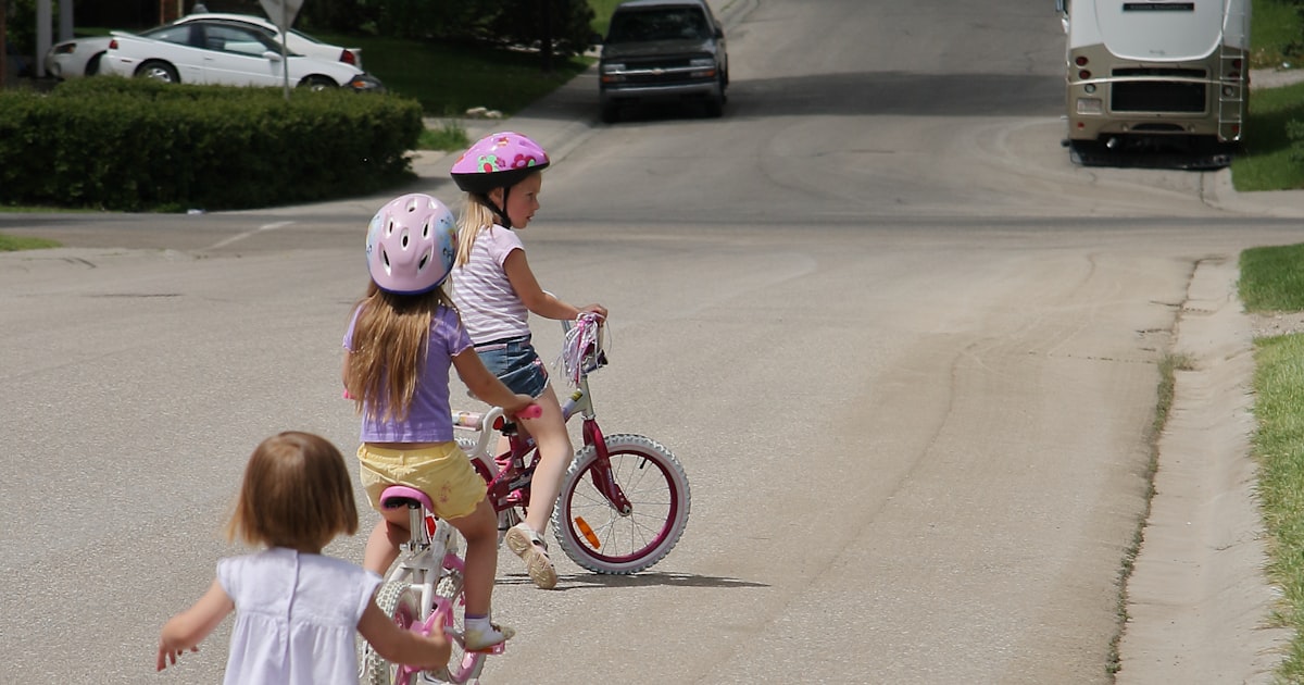 Children riding bikes and walking on a Cleveland neighborhood street in summer