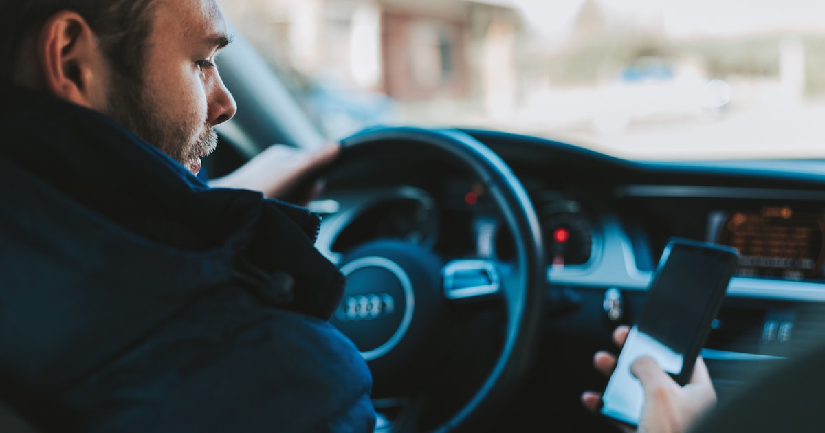 Hand holding a smartphone while driving, illustrating Ohio hands-free law violations