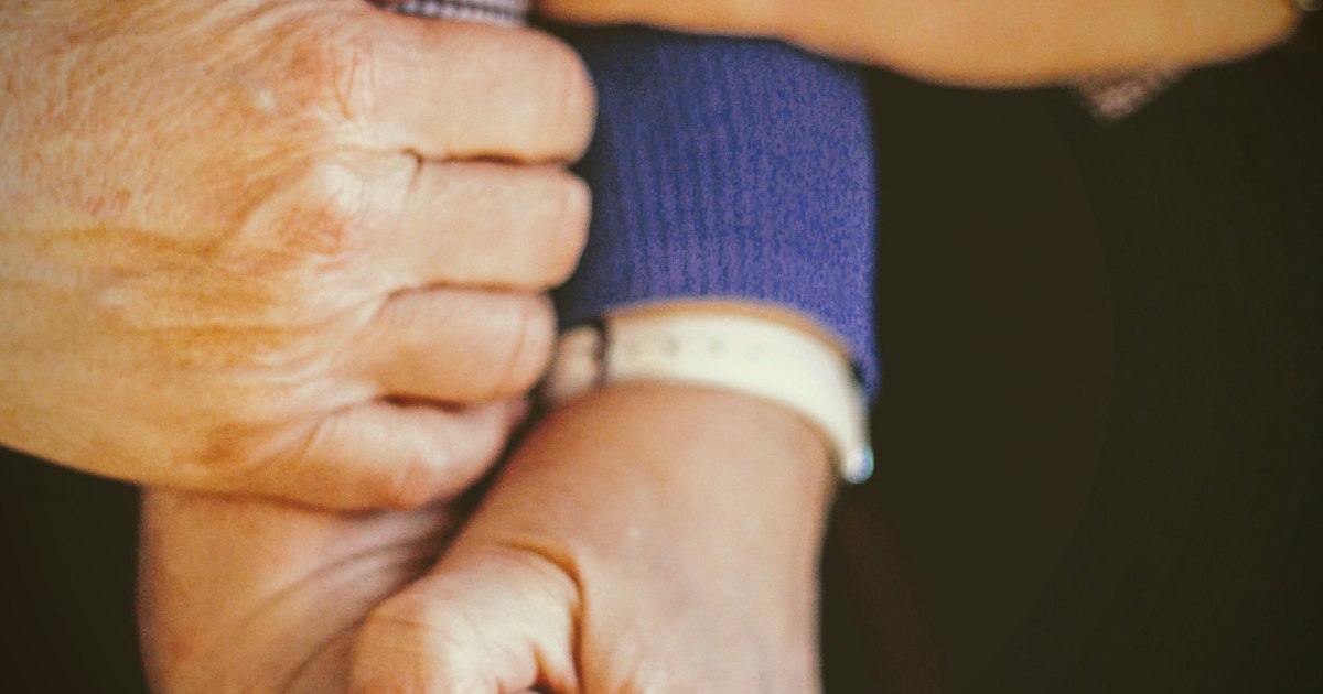 Caregiver holding the hand of an elderly nursing home resident