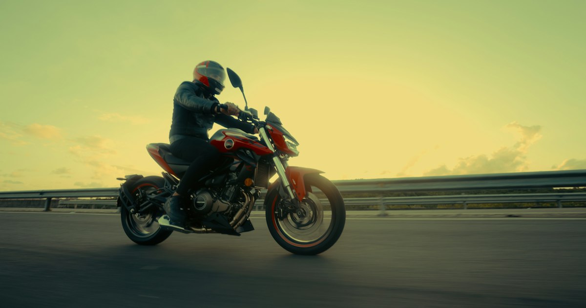 A motorcyclist riding into low autumn sunlight on a Northeast Ohio highway
