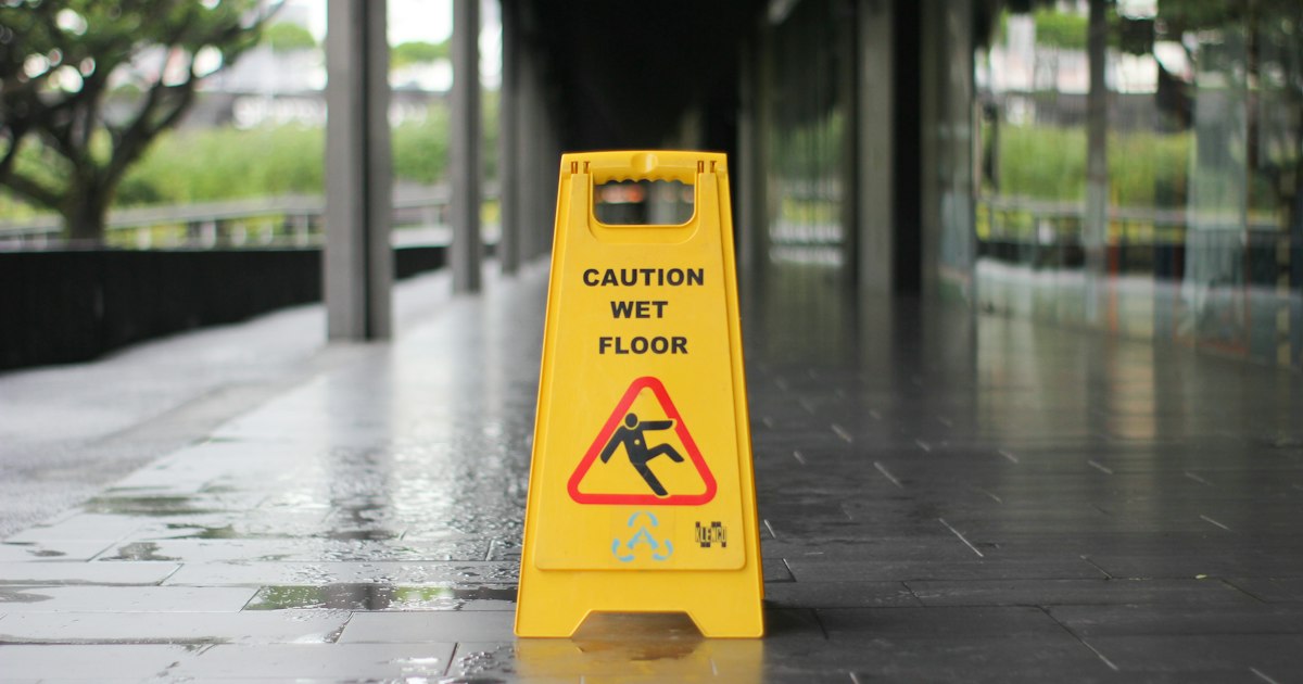 Yellow wet floor caution sign on a slick indoor floor at a store entrance